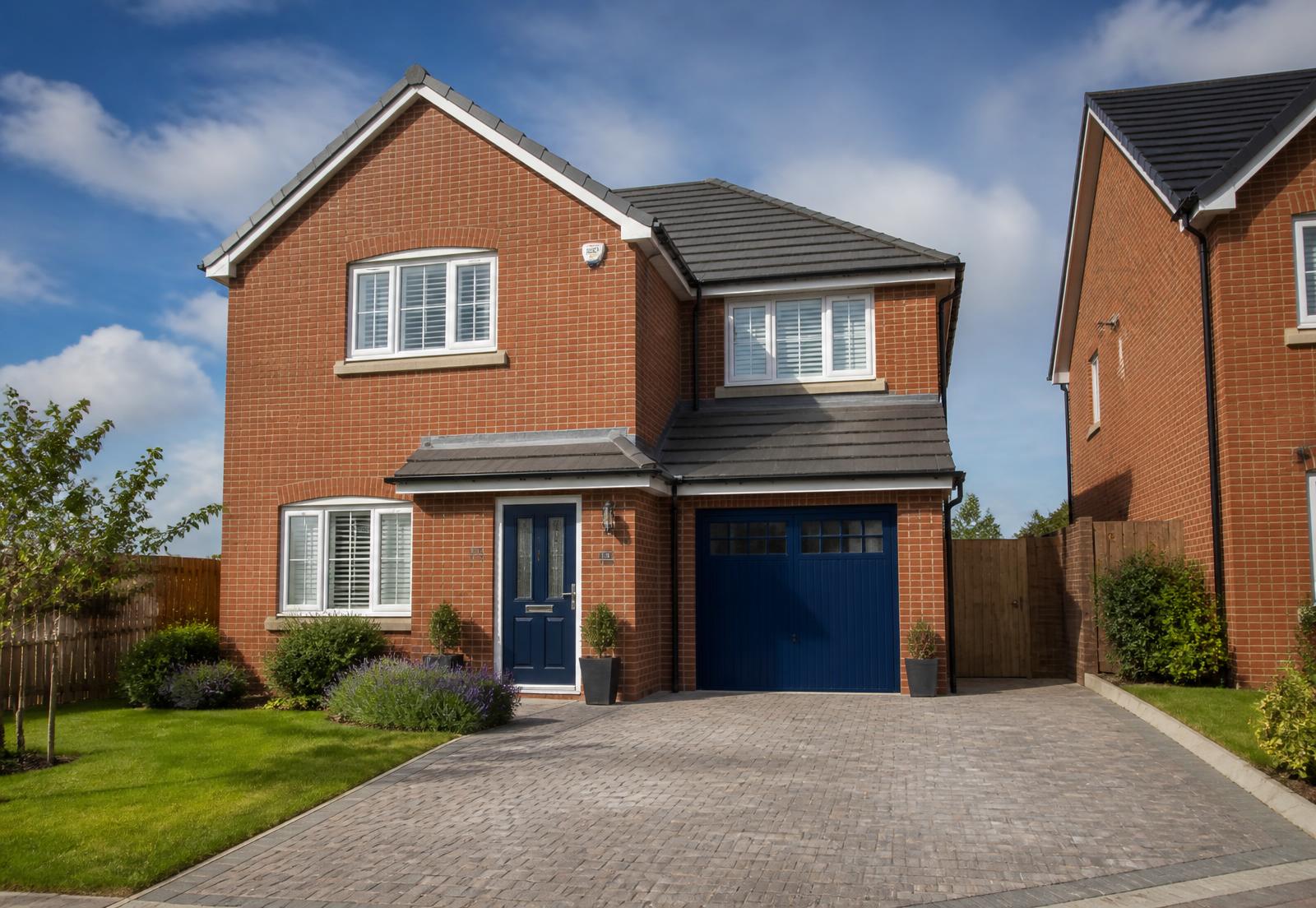 Modern new-build red brick house with a navy front door